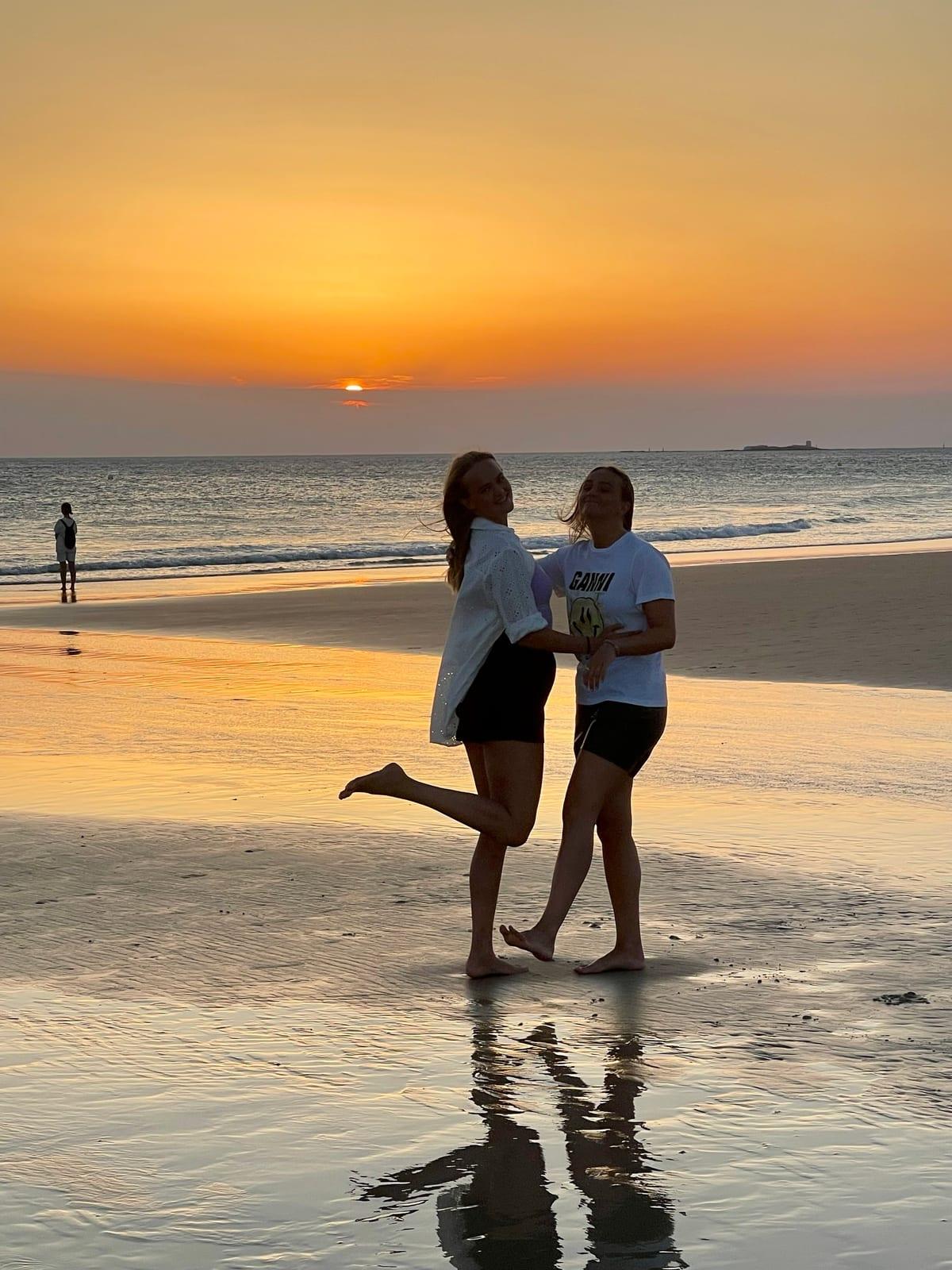 To unge kvinder på stranden i solnedgang